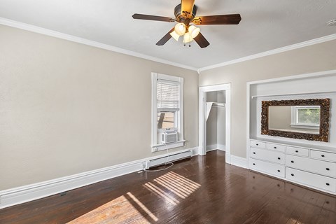A room with a ceiling fan and a wooden floor.