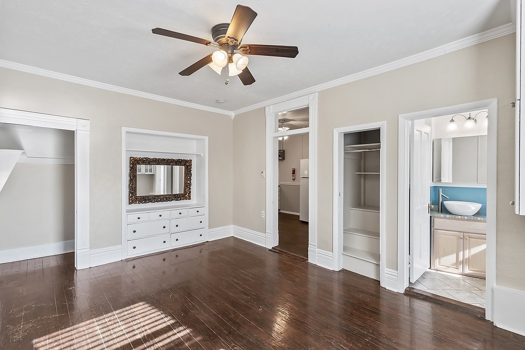 A room with a ceiling fan and a dresser with a mirror.