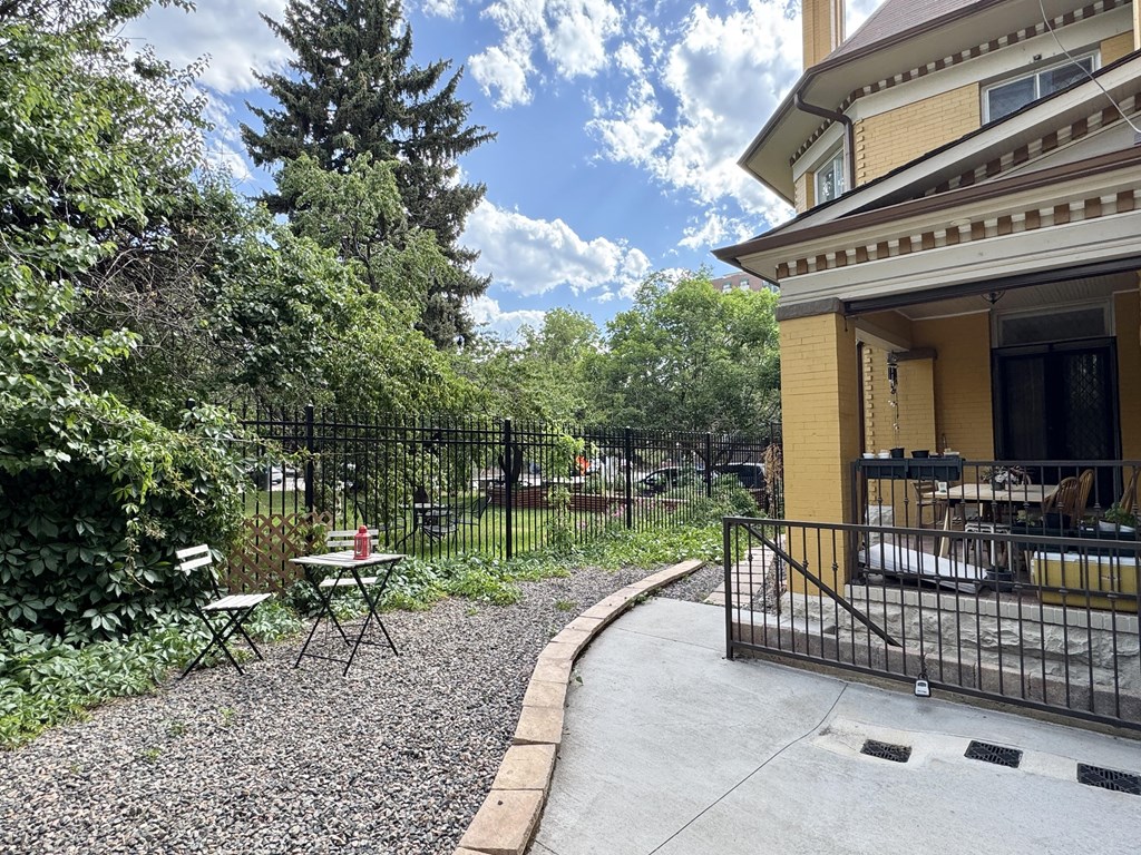 A yellow house with a black fence and a gravel pathway.