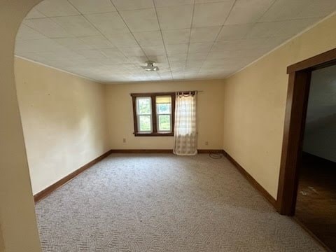 A room with a carpeted floor and a window with curtains.
