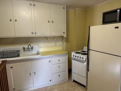 A kitchen with white cabinets and a white fridge.