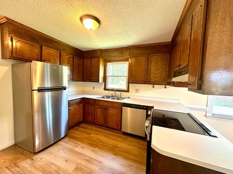 A kitchen with wooden cabinets and a stainless steel refrigerator.