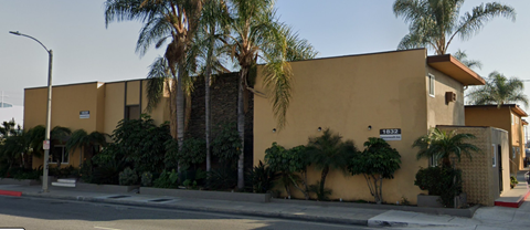 A yellow building with a red street sign in front of it.