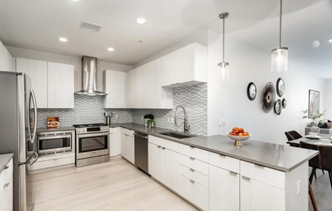 A modern kitchen with white cabinets and stainless steel appliances.