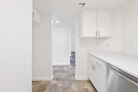 A kitchen with white cabinets and a tiled floor.