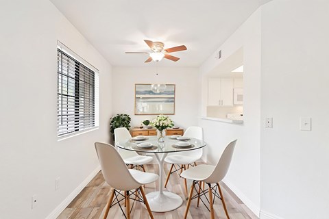 A dining room with a glass table and white chairs.