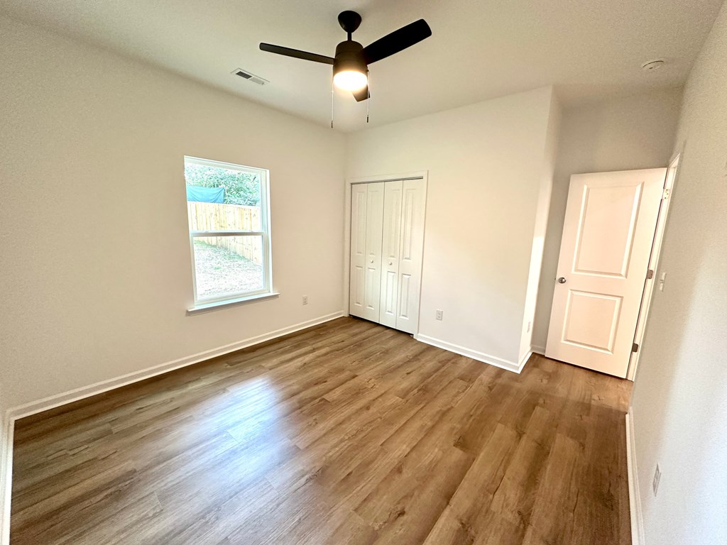 A room with a ceiling fan and wooden flooring.
