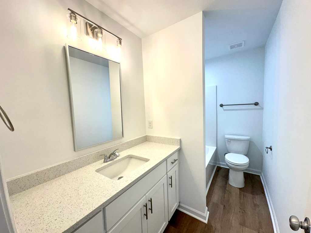 A bathroom with a toilet, sink, and mirror.