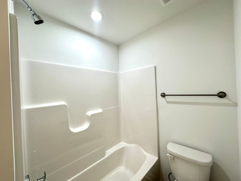 A white toilet sits next to a walk-in shower.