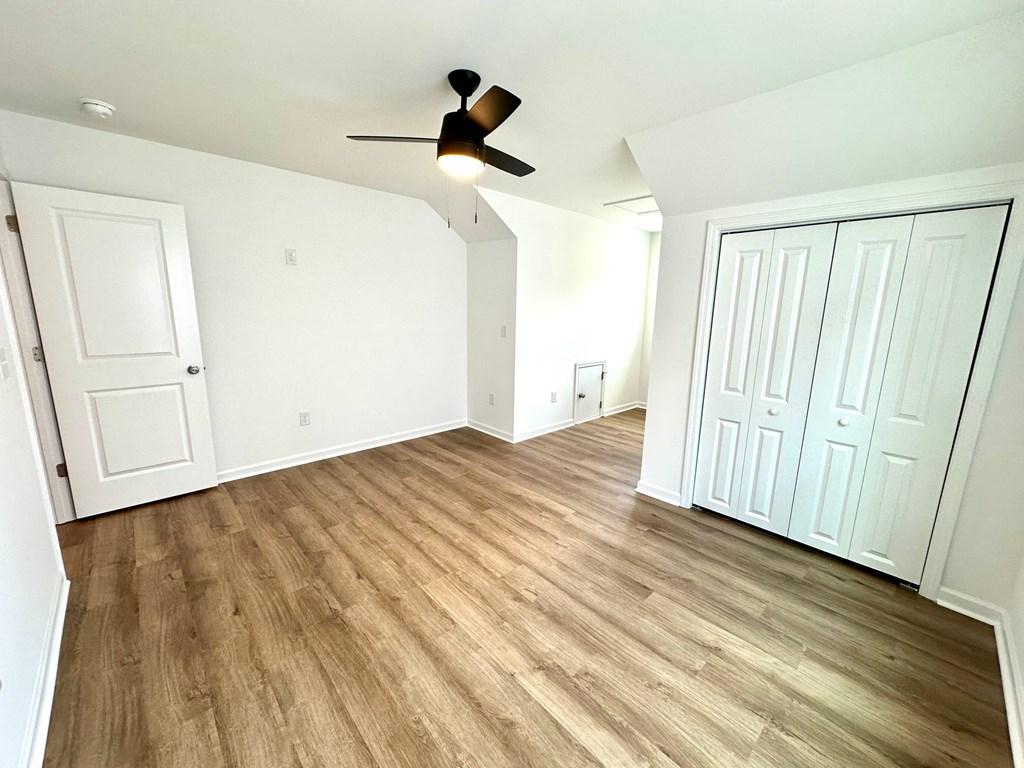 A room with a ceiling fan and wooden flooring.