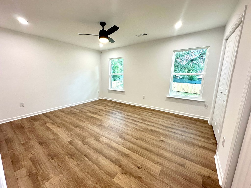 A room with a ceiling fan and two windows.