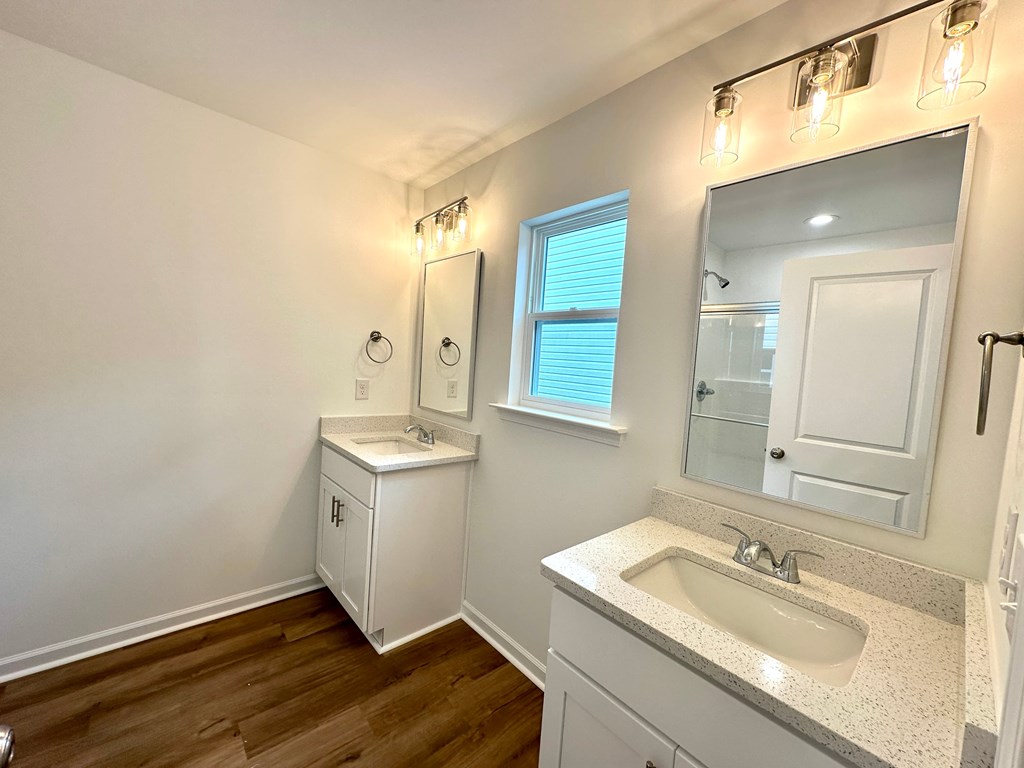 A bathroom with a sink, mirror, and lighting fixtures.