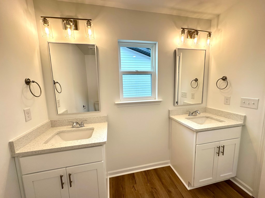 A bathroom with a sink, mirror, and lighting fixtures.