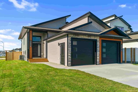 A modern house with a grey exterior and a black garage door.
