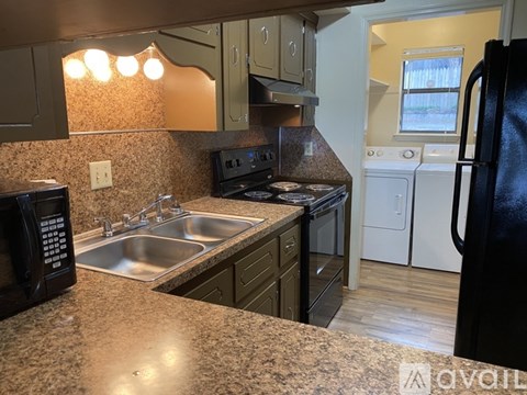 A kitchen with a black refrigerator and a black microwave.