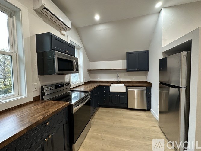 A modern kitchen with black cabinets and stainless steel appliances.