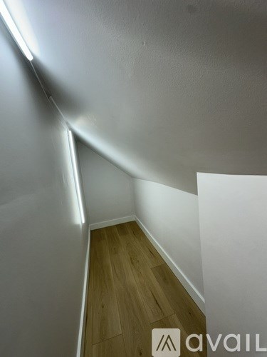 A wooden floor leads up a white wall.