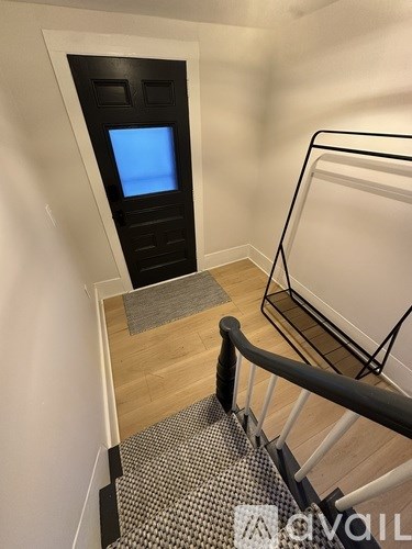 A staircase with a black railing and a black door with a blue screen on it.