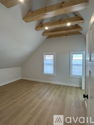 A room with wooden beams on the ceiling and a door on the right.