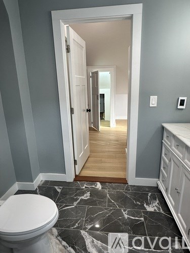 A bathroom with a toilet and a marble floor.