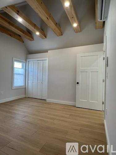 A room with wooden floors and a window with blinds.