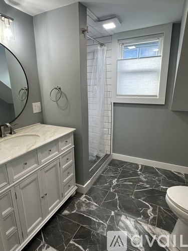 A bathroom with a marble floor and white fixtures.