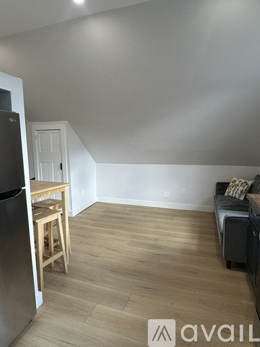 A kitchen with a refrigerator, a table and a couch.