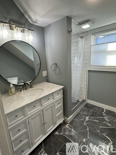 A bathroom with a marble floor and a white vanity.