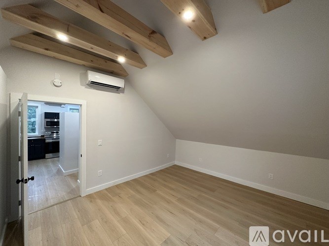 A room with wooden beams on the ceiling and a doorway leading to another room.