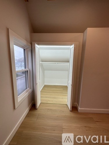 A room with wooden flooring and a window on the left side.