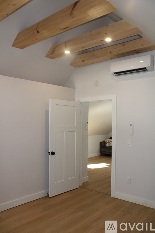 A room with a white door and a wooden ceiling.