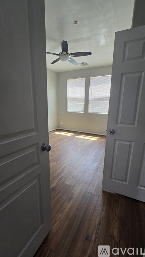 A room with a ceiling fan and wooden floors.