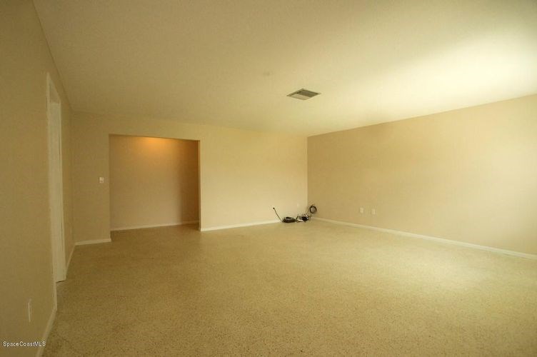 A room with a carpet floor and a ceiling fan.