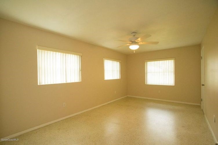 A room with a ceiling fan and two windows.