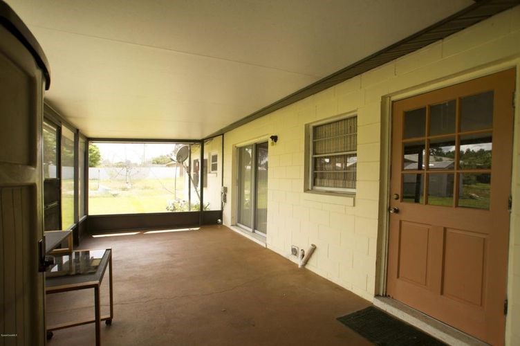 A room with a brown door and a table with a bottle on it.