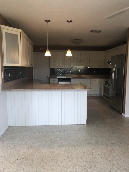 A kitchen with a white counter and a refrigerator.