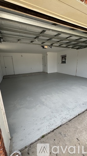 A spacious garage with a concrete floor and a white ceiling with visible beams.