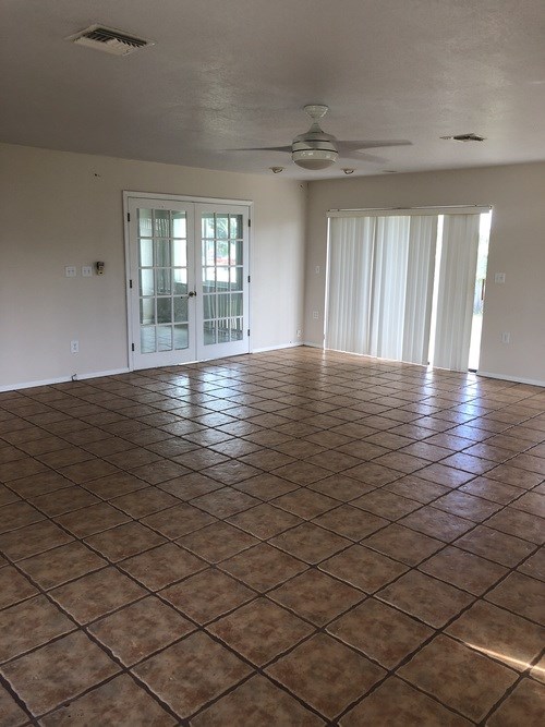 A room with a brown tile floor and a ceiling fan.