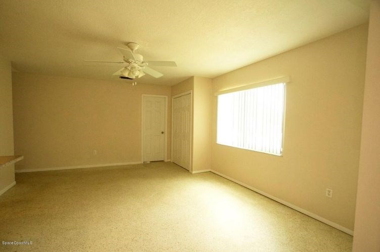 A room with a ceiling fan and a window with blinds.