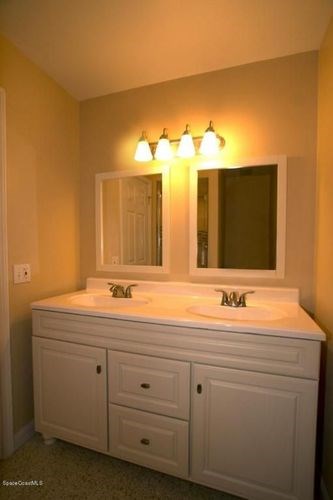 A bathroom with a white vanity and a mirror above it.