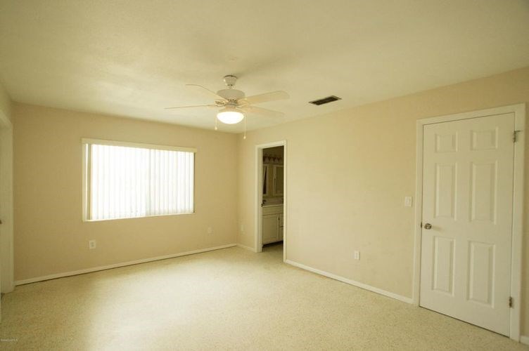 A room with a ceiling fan and two doors.