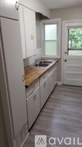 A kitchen with white cabinets and a wooden countertop.