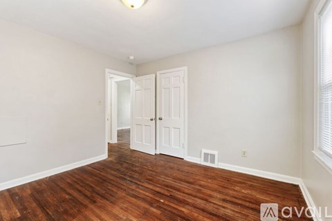 A hallway with a dark wood floor and white walls.