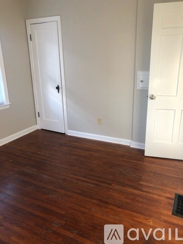 A room with a white door and a brown floor.