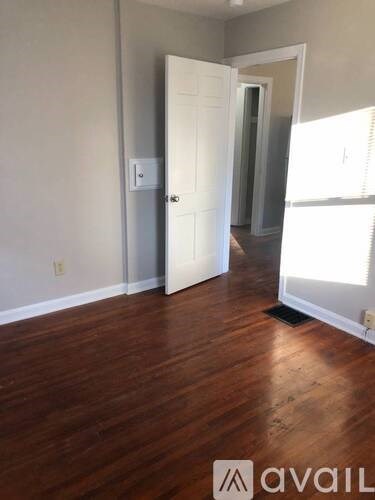 A room with a white door and wooden floor.