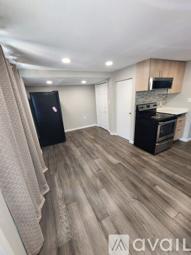 A kitchen with a black fridge and wooden flooring.
