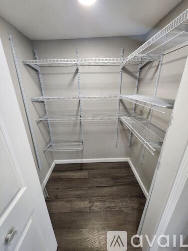A walk-in closet with shelving and a wooden floor.