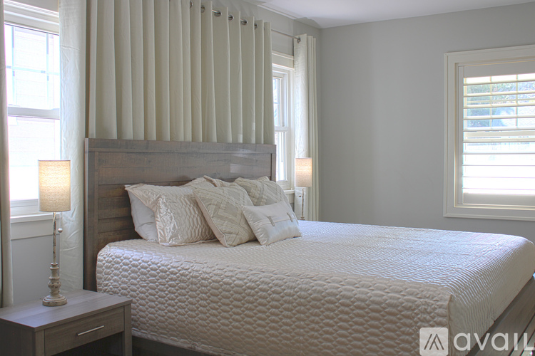 A bedroom with a large bed and a window with blinds.