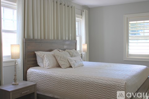 A bedroom with a large bed and a window with blinds.