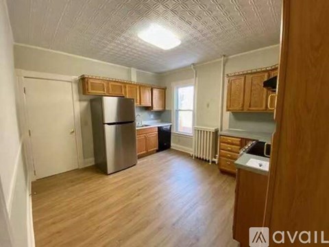 A kitchen with wooden cabinets and a stainless steel refrigerator.